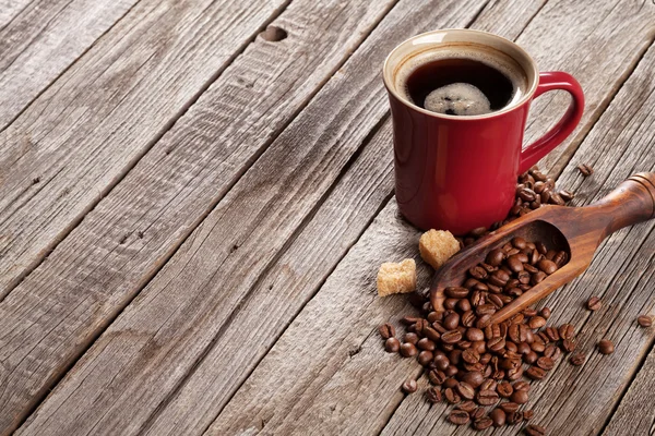 Koffiekopje en bonen op tafel — Stockfoto