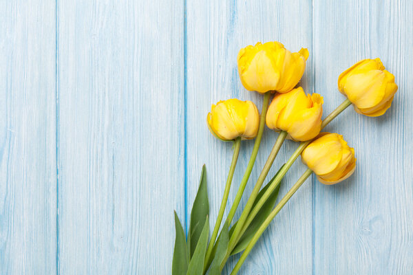 Yellow tulips over wooden table