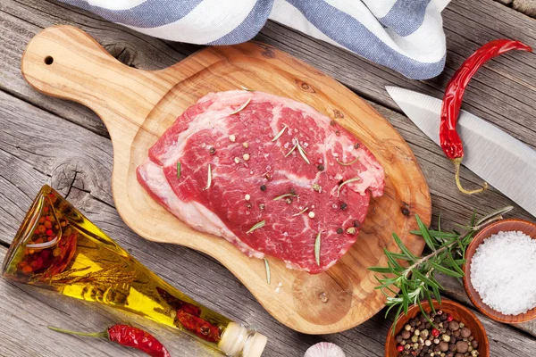 Bistecca di manzo con spezie, erbe aromatiche e bottiglia di olio — Foto Stock