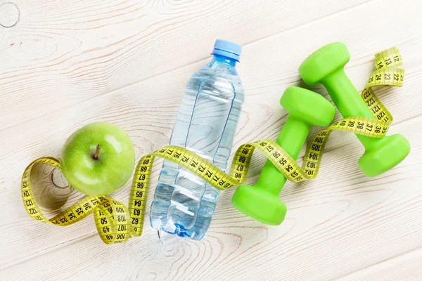 Bottle, tape measure, apple and dumbbells — Stock Photo, Image