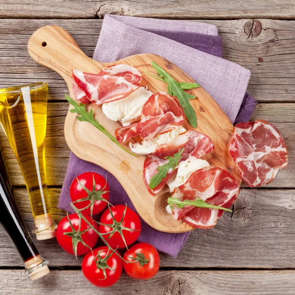 Prosciutto, mozzarella och tomater och flaskor olja — Stockfoto