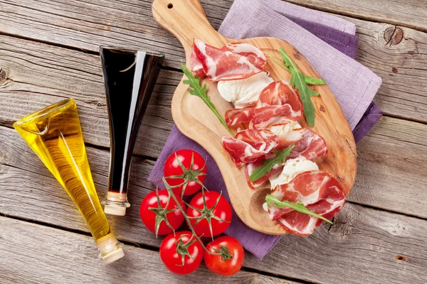 Prosciutto and mozzarella on wooden table — Stock Photo, Image