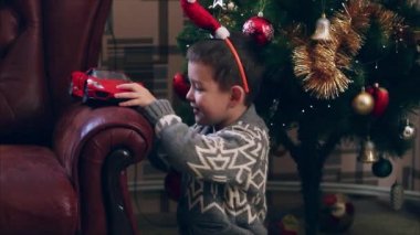 Komik Noel Baba'nın şapkalı küçük çocuk oyuncak araba ile oynuyor 