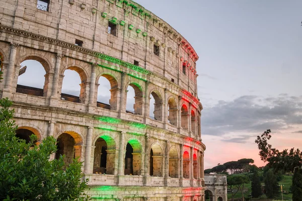 El famoso Coliseo de Roma iluminado en tricolor bandera italiana al atardecer — Foto de Stock