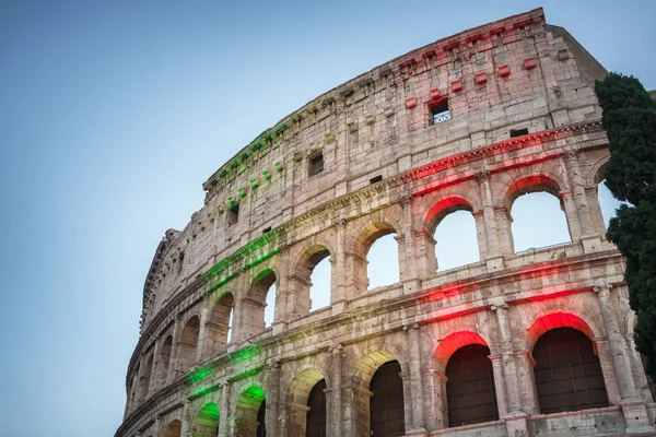 El famoso Coliseo de Roma iluminado en tricolor bandera italiana al atardecer — Foto de Stock