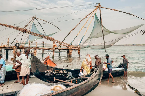 Неизвестные рыбаки стоят рядом со своими лодками рядом с китайскими рыболовецкими сетями в Форт Кочи, штат Керала, Индия — стоковое фото