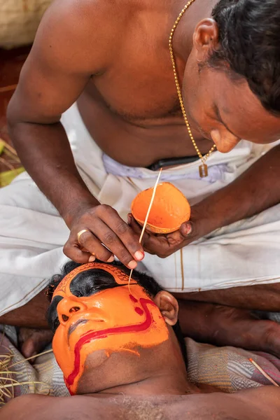 Индуистские священники делают макияж для Тхейям исполнитель во время храмового фестиваля — стоковое фото