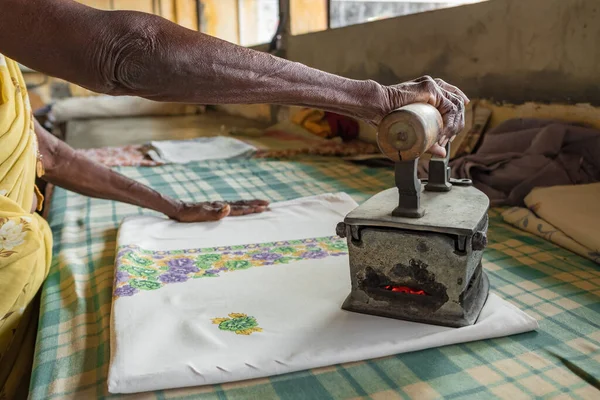 Unbekannte Seniorin bügelt in Indien Kleidung mit einem alten kohlebeheizten Bügeleisen — Stockfoto