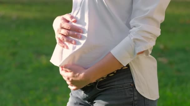 Donna incinta in camicia bianca accarezza delicatamente una grande pancia all'aperto — Video Stock