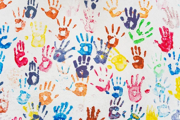 Parede branca com impressões coloridas de mãos multicoloridas. — Fotografia de Stock