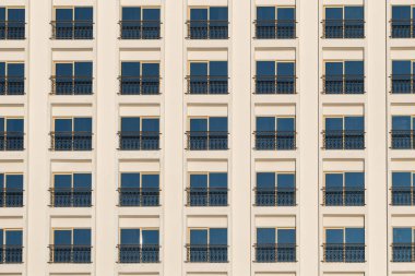 Beyaz duvarda birçok penceresi olan bir otel binası cephesi