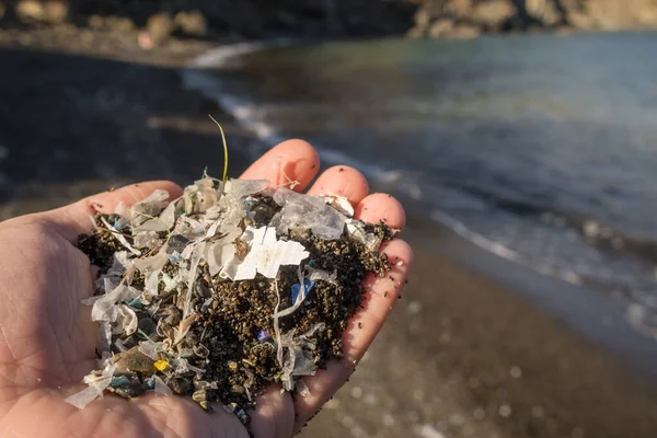 Pequenas peças de plástico e microplásticos na praia de areia — Fotografia de Stock