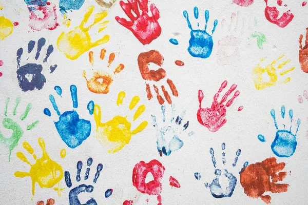 White wall with colorful multicolored hand prints. — Stock Photo, Image