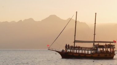 Akdeniz 'de gün batımında yelken açan turist teknesi, Antalya, Türkiye. 