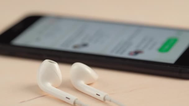 Smartphone s Clubhouse pokles v audio chatu aplikace a sada sluchátek v blízkosti — Stock video