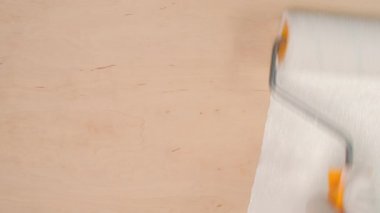 Beyaz boyayla ahşap yüzeyi boyayan paten.