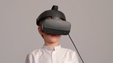 Evde sanal gerçeklik kulaklığıyla oynayan genç bir çocuk..