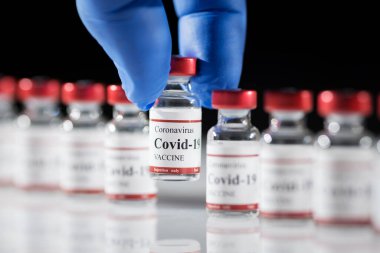 Doktorlar lateks mavi eldivenlerde Covid-19 koronavirüs aşısı şişesi olduğunu söylüyor..