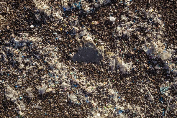 Pequenas peças de plástico e microplásticos na praia de areia — Fotografia de Stock