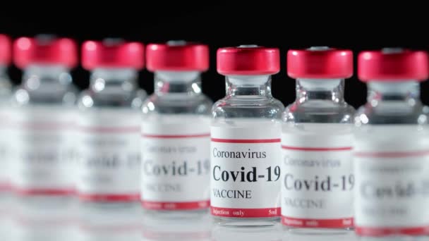 Врачи в латексных перчатках берут флакон с вакциной Ковид-19 со стола — стоковое видео