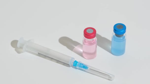 Неуказанные два флакона вакцины и шприц на столе — стоковое видео