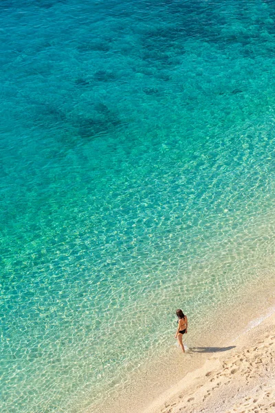 Mujer joven entra en aguas turquesas transparentes del mar Mediterráneo — Foto de Stock