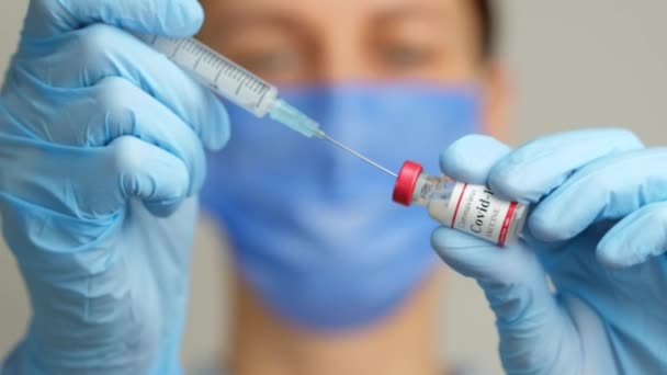 여자 의사가 주사기와 코로나 바이러스 백신 병을 가지고 있다. — 비디오