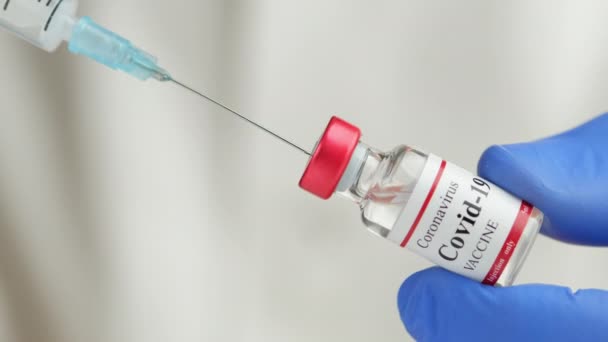 Врач держит коронавирусную вакцину и шприц для предотвращения инфекции COVID-19 — стоковое видео