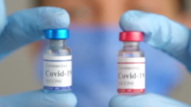 Arzt hält zwei verschiedene covide Coronavirus-Impfflaschen in den Händen. — Stockvideo