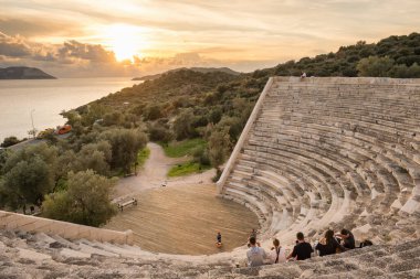 Türkiye 'nin Kas kentindeki Antiphellos antik şehir amfitiyatrosundan gün batımının keyfini çıkaran kimliği belirsiz kişiler
