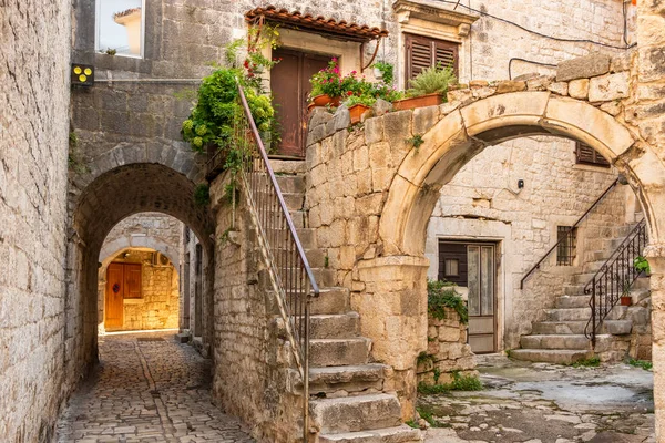 Trogir şehrinde çiçek saksıları ve temiz çamaşırları olan resim gibi bir cadde. — Stok fotoğraf