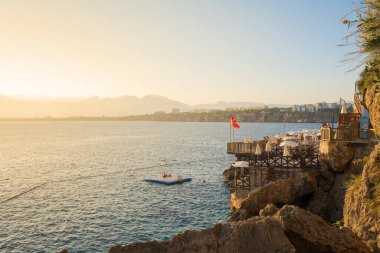 Türkiye 'nin Antalya kentinde gün batımında Akdeniz kıyısında uçurumun kenarındaki restoran