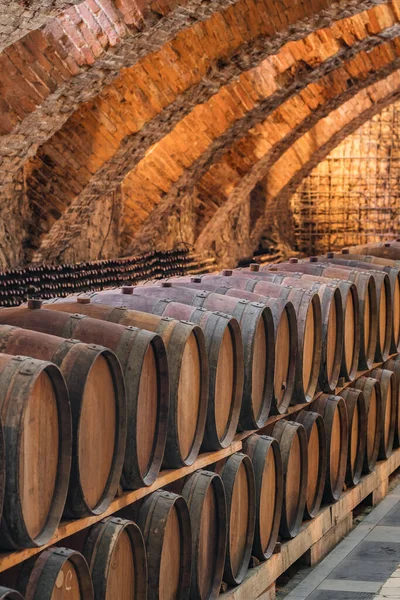 Velhos barris de madeira com vinho nas antigas caves medievais — Fotografia de Stock