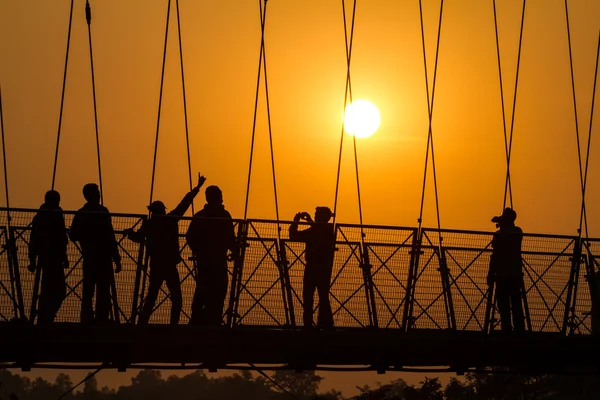 Le persone sagome sul ponte sul tramonto — Foto Stock