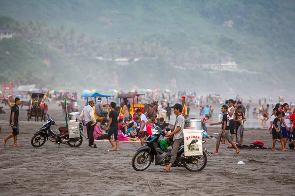 Food vendors and tourists on the black sand — Stock Photo, Image