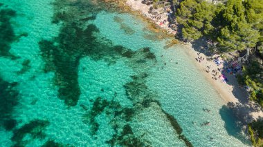 Playa de Formentor 'un Mallorca' daki Cala Pi de la Posada körfezindeki hava manzarası. Cap Formentor, Mayorka, Balear Adaları, İspanya 'da turkuaz sularda yüzen insanların olduğu çarpıcı bir sahil..