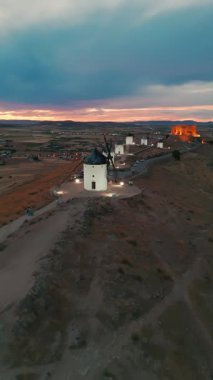 Consuegra 'nın tarihi yel değirmenlerinin geceleri havadan görünüşü, Castilla-La Mancha, İspanya. Alacakaranlıktaki tepelerde Don Kişot karakterinin eski tarihi yel değirmenleri. Molinos de Viento de Consuegra