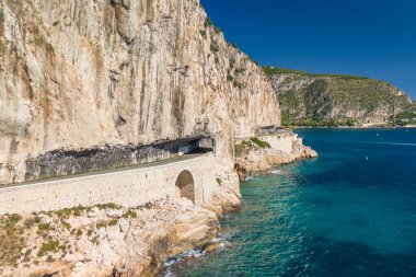 Nice ve Monako arasındaki Fransız Riviera kıyı şeridi havadan görünüyor. Bir araba Corniche Inferieure yolu boyunca Akdeniz 'in turkuaz sularının üzerindeki yüksek uçurumlardan geçiyor.