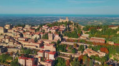 San Marino 'nun görkemli üç kulesinin, tarihi ortaçağ mimarisinin ve güzel bir tepe manzarasının yer aldığı eski bir şehrin insansız hava aracı görüntüsü..