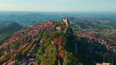 San Marino 'nun görkemli üç kulesinin, tarihi ortaçağ mimarisinin ve güzel bir tepe manzarasının yer aldığı eski bir şehrin insansız hava aracı görüntüsü..
