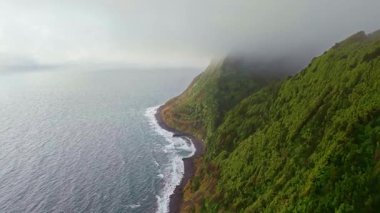 Portekiz, Azores 'te bulutlu ve sisli havada Miradouro da Ponta do Sossego' dan görülen Sao Miguel adasının yüksek yeşil uçurumları. Dramatik Atlantik adası doğası olan manzaralı kıyı manzarası..