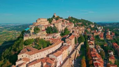 San Marino 'nun görkemli üç kulesinin, tarihi ortaçağ mimarisinin ve güzel bir tepe manzarasının yer aldığı eski bir şehrin insansız hava aracı görüntüsü..