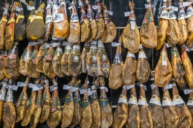 Oviedo, İspanya - 23 Temmuz 2024: İspanyol Jamon Iberico ve Serrano jambonları modern bir süpermarket gurme bölümünde etiketli Black metal raflarda sallanıyor.