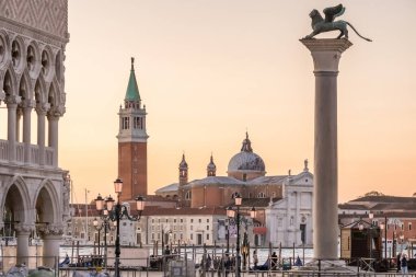 Venedik, İtalya Saint Mark 'ın Kanatlı Aslanı' nın silueti günbatımı gökyüzüne karşı, San Giorgio Maggiore kilisesi ve gölün karşısındaki çan kulesi.