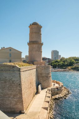 Mavi Akdeniz kıyısındaki Saint Jean Kalesi 'ndeki Fanal deniz feneri kulesi ve taş tahkimatı manzarası, Marsilya, Fransa