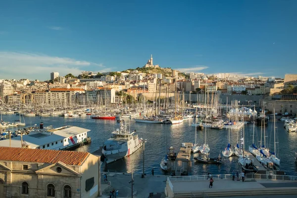 Marsilya, Fransa - 14 Eylül 2024: Vieux Limanı manzarası arka plandaki tepede Notre Dame de la Garde kilisesi olan tekne ve yatlarla dolu.