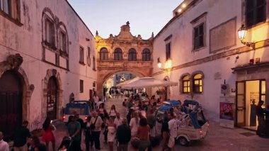 Ostuni, İtalya - 22 Ağustos 2025: Alacakaranlıkta Ostuni. İnsanlar Puglia İtalya 'da sıcak bir yaz akşamı romantik şehir merkezinin tarihi kireçtaşı sokaklarında yürüyorlar..