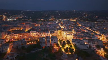 Geceleri İtalya 'nın Puglia kentindeki Cisternino kasabasının hava manzarası. Beyaz tarihi merkez, Güney İtalya 'daki karanlık Itria Vadisi manzarasının üzerinde ışıklarla parıldıyor..
