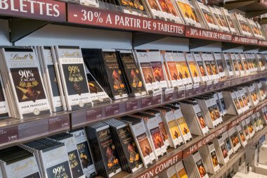 Oloron Sainte Marie, Fransa - 26 Ağustos 2024: Çeşitli Lindt çikolata ürünleri, hediye kutuları ve fabrika butiği raflarında raflarda sergilenen altın sarısı şekerlemeler