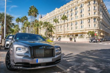 Cannes, Fransa - 21 Eylül 2024: Cote d Azur 'un arka planında Carlton Hotel binası olan caddede park etmiş gümüş renkli Rolls Royce lüks bir arabanın ön görüntüsü.